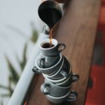 person holding gray stainless steel pitcher bside window