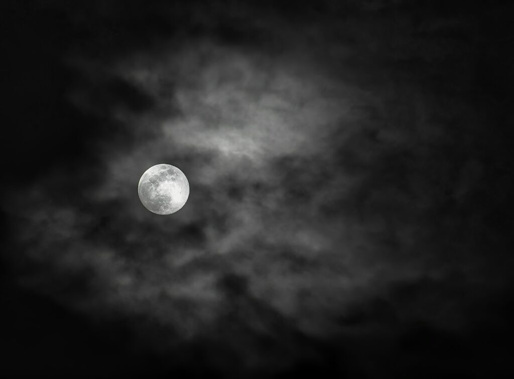 a full moon is seen through the clouds